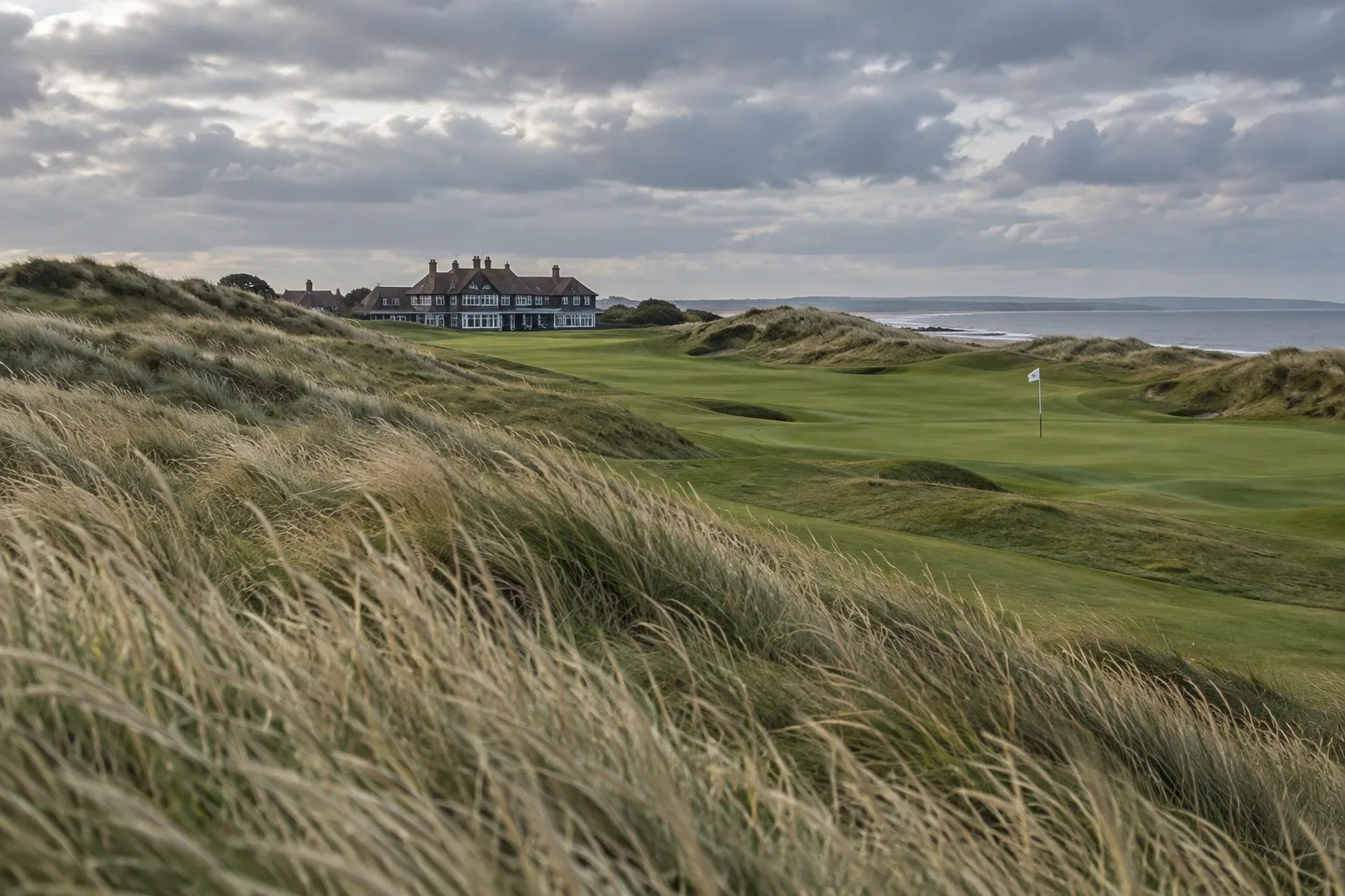Royal Birkdale: Course Guide, History, and Visitor Tips 1 Royal Birkdaleu2019s rolling links course winds between golden dunes toward the clubhouse, with a flag beneath a cloudy sky.